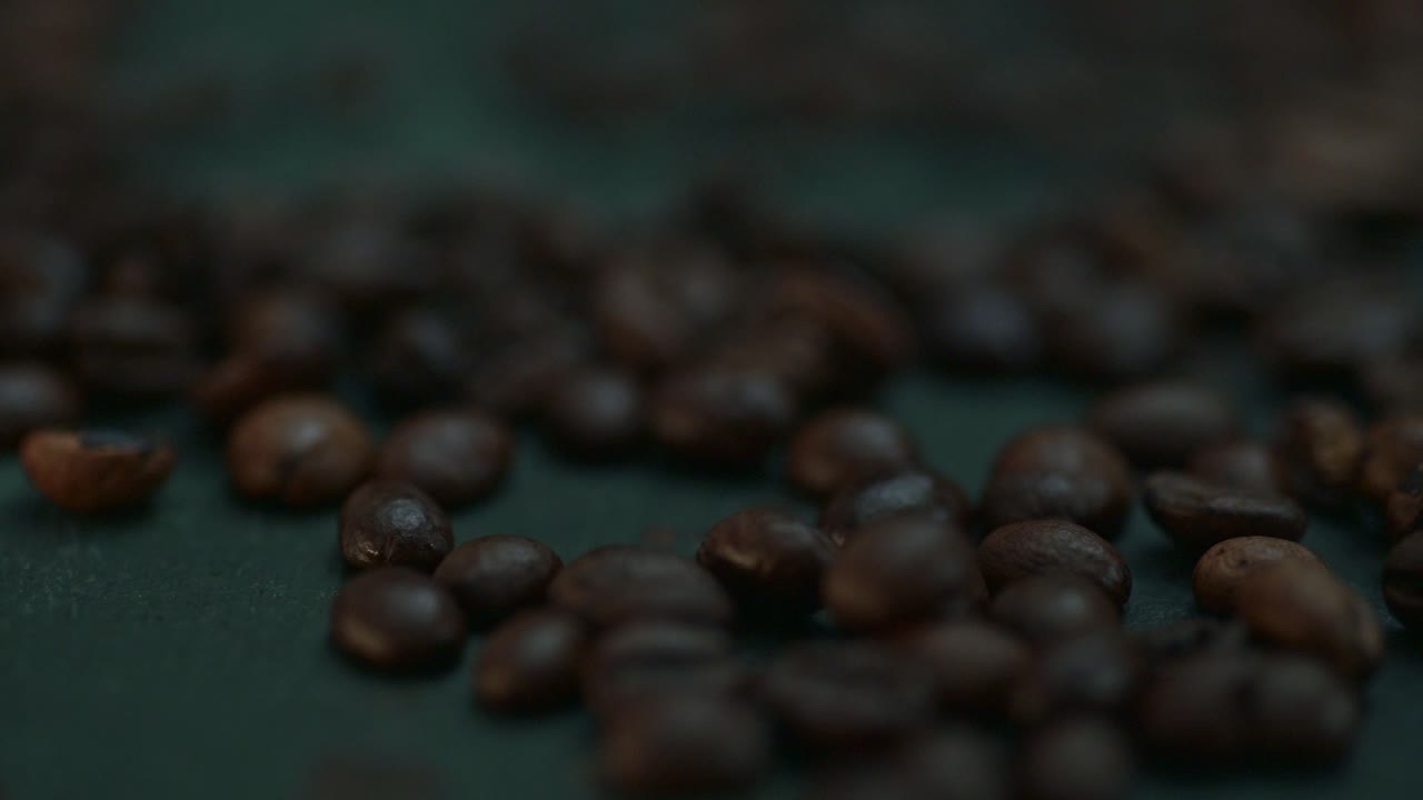 granos de café de primer plano cayendo, derramándose sobre la mesa oscura