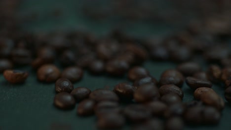 Close-up-coffee-beans-falling,-spilling-onto-the-dark-table