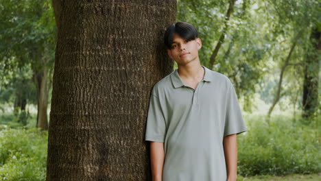 portrait of a man leaning against a tree