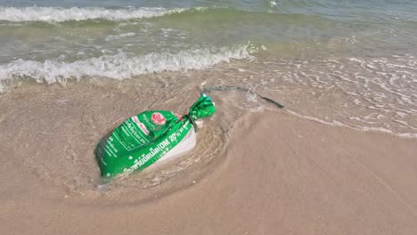 una bolsa de plástico se lava en una playa de arena.