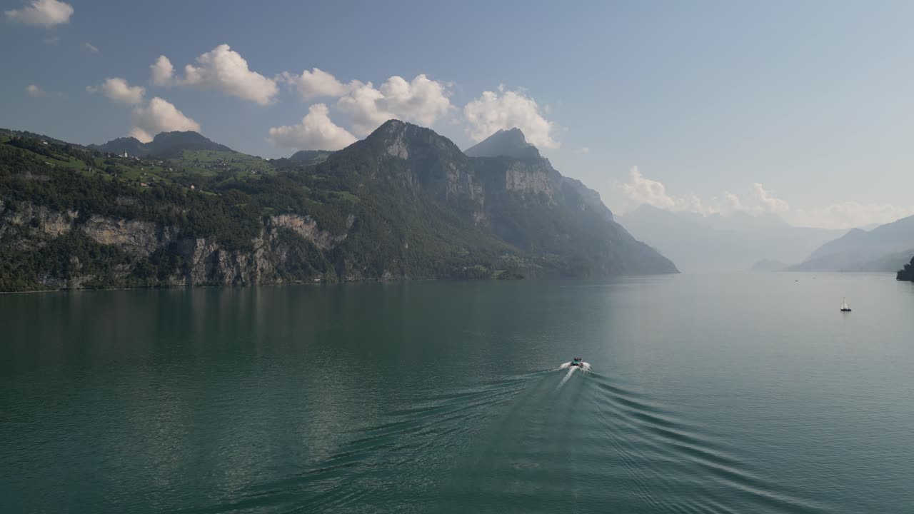 큰 호수를 가로지르는 부드러운 움직임 이국적인 모험 보트 드문 위치 세계 끝의 지평선을 향해 타고 거대한 산이 지역을 둘러싸고 언덕 위의 구름