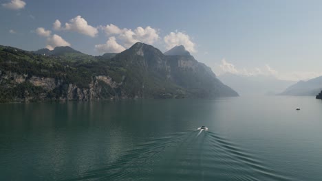 movimiento suave volando a través de un gran lago exótico lugar raro para la aventura barco conduciendo hacia el horizonte fin del mundo montañas masivas que rodean el área nubes por encima de las colinas