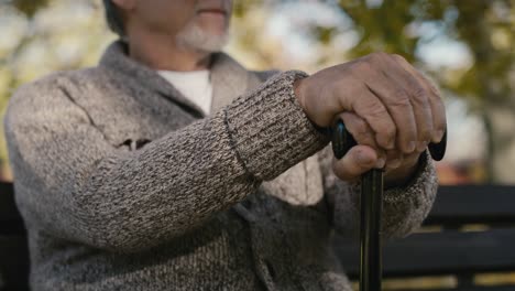 Close-up-serious-old-caucasian-man-sitting-on-bench-in-park