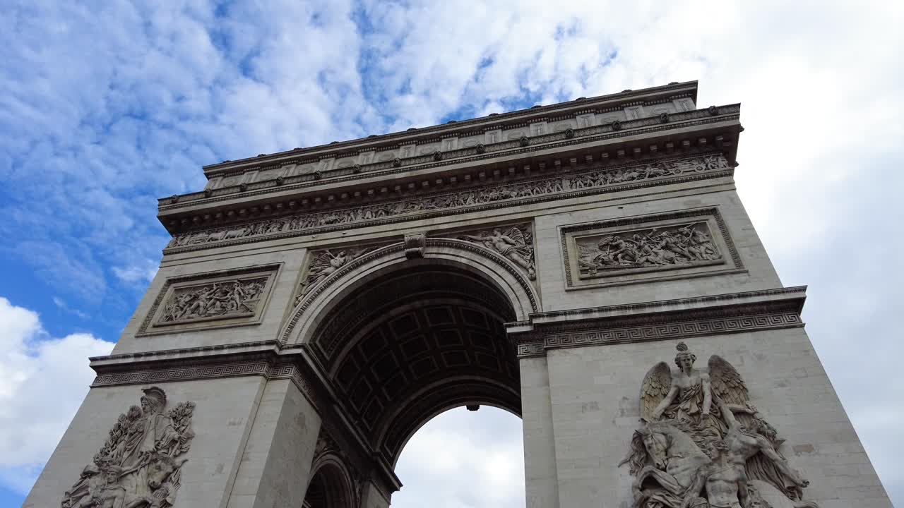 la parte superior del arco del triunfo en un cielo azul nublado en parís, francia