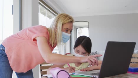 Mother-wearing-face-mask-helping-daughter-with-homework-at-home