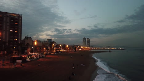 high aerial drone shot flying over beautiful barceloneta beach in barcelona during night