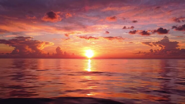 Ein wunderschöner Sonnenuntergang über ruhigem Wasser: Eine bezaubernde Mischung aus Farben und Gelassenheit, während die Sonne an einem ruhigen Abend untergeht und Reflexionen auf die Meeresoberfläche wirft.