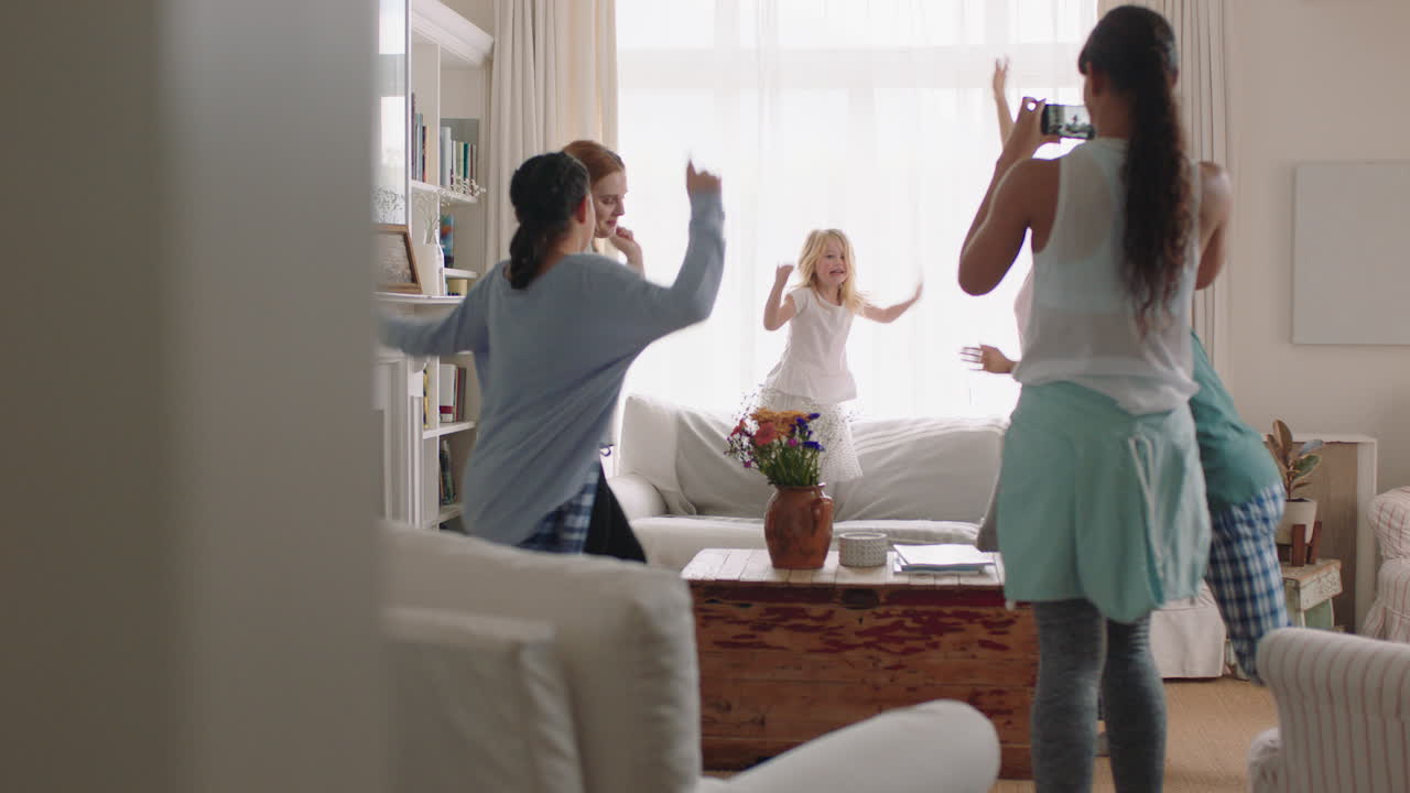 행복한 다민족 가족 집에서 춤을 추고 재미있게 춤을 즐기는 십대 소녀는 스마트폰을 사용하여 흥미진진한 주말의 비디오를 소셜 미디어에서 공유합니다.
