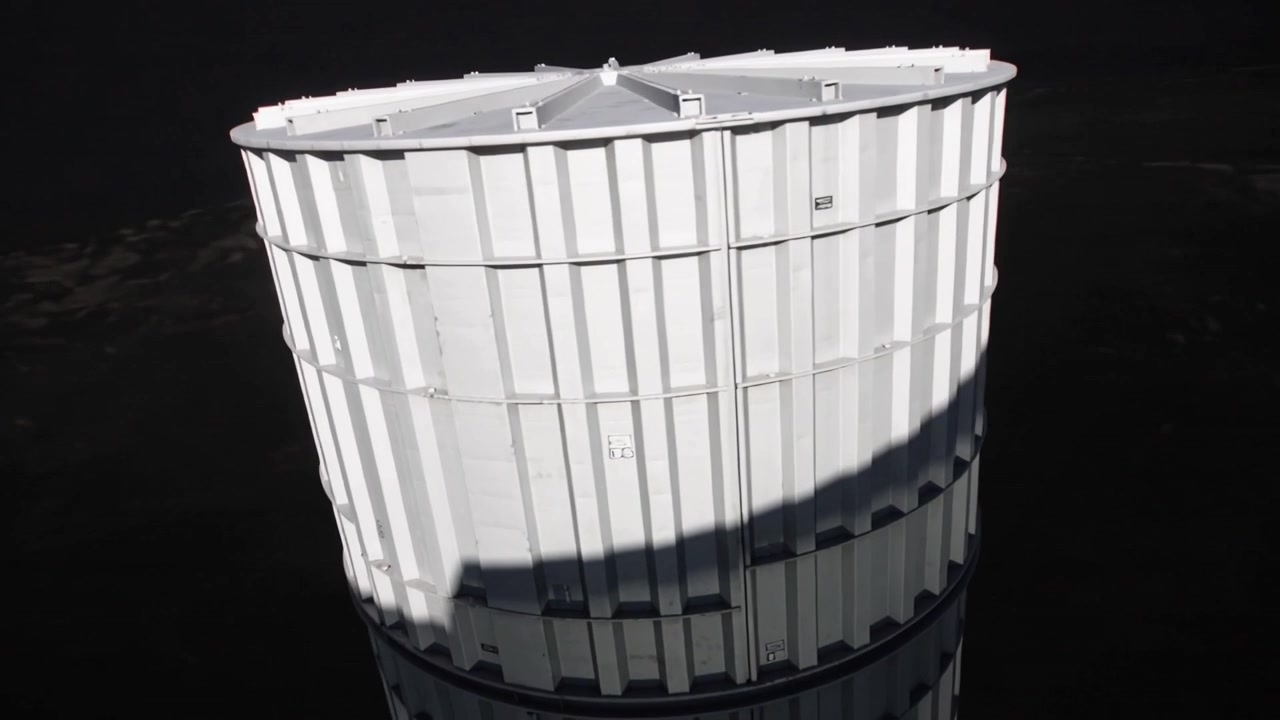 Câmera de drone giratória iniciando a revelação de um grande silo branco em um local de utilidade, com uma sombra varrendo.