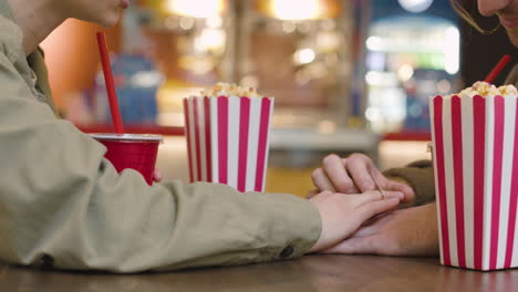 Pareja-Amorosa-Tomándose-De-La-Mano-Mientras-Se-Sienta-A-La-Mesa-En-El-Snack-Bar-Del-Cine