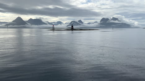 Amazing-clouds-crawling-over-the-mountains-of-Helgeland-coast-while-the-rain-is-pouring-on-the-surface-of-the-ocean,-driving-shot