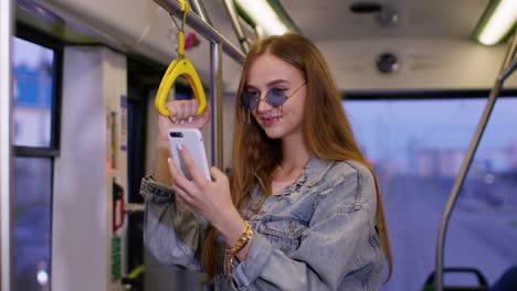 woman playing on smartphone, chatting, texting, browsing social media while traveling by bus to city