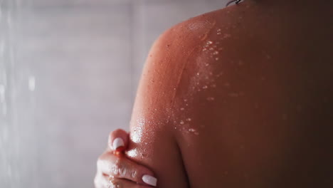 mujer limpia la piel con exfoliante en la unidad de ducha de cerca. dama utiliza producto cosmético natural para exfoliar la piel seca en el baño. rutina de belleza en casa
