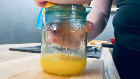 juicing fresh orange for healthy juice on kitchen counter from side shot in slow motion