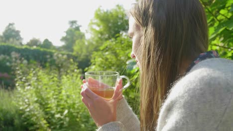 Junge-Frau-Mit-Langen-Haaren-Genießt-Tee-Im-Hellgrünen-Garten-über-Der-Schulter