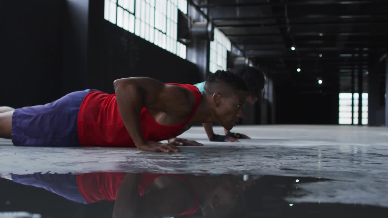 Fitness partners following male lead, doing in-sync push-ups, wet reflection and neon Share linking