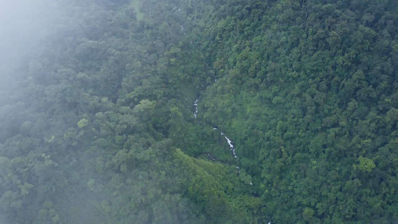 An awe-inspiring aerial shot of Catarata del Toro river in Costa Rica ending over the cloudy Mountains