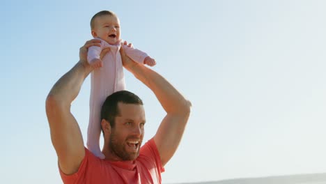 front view of mid adult caucasian father carrying baby on shoulder on a sunny day 4k