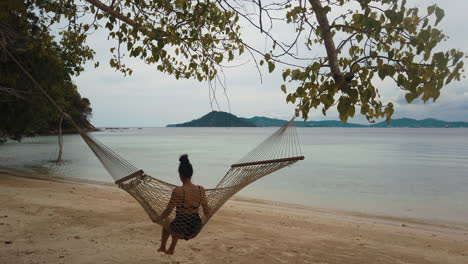 Female-tourist-relaxes-swinging-in-a-hammock-on-the-beach-in-Borneo