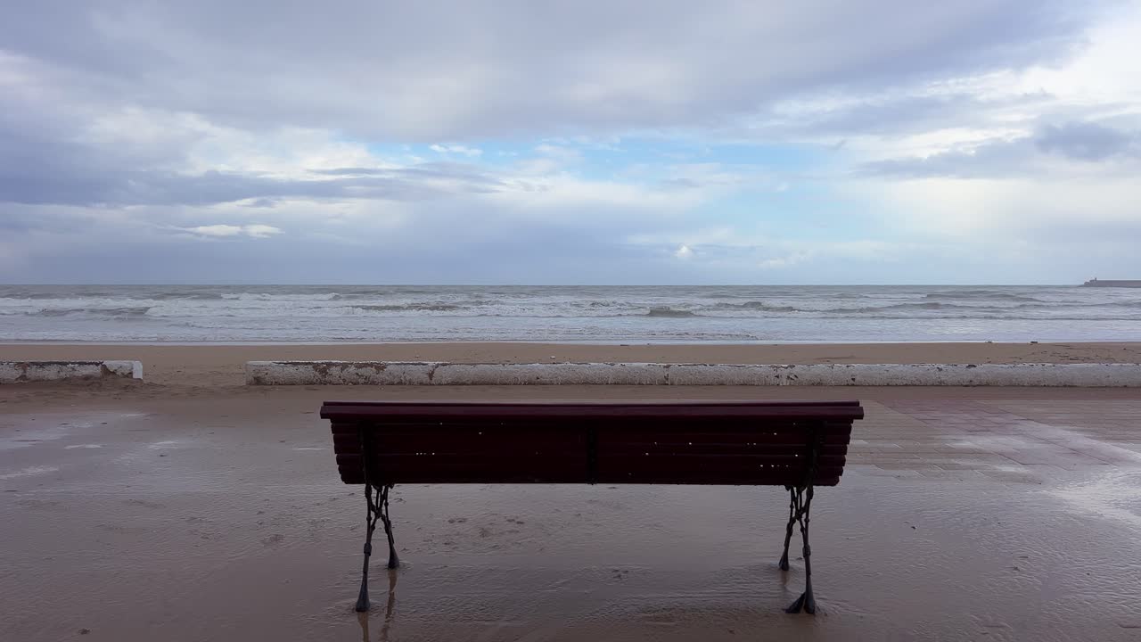 A solitary bench on the Atlantic Ocean promenade with crashing waves.