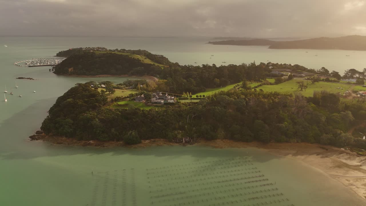 Sweeping aerial panoramic view of Waiheke Island at sunset, showing coastline, beaches, and calm waters. Scenic travel destination, New Zealand