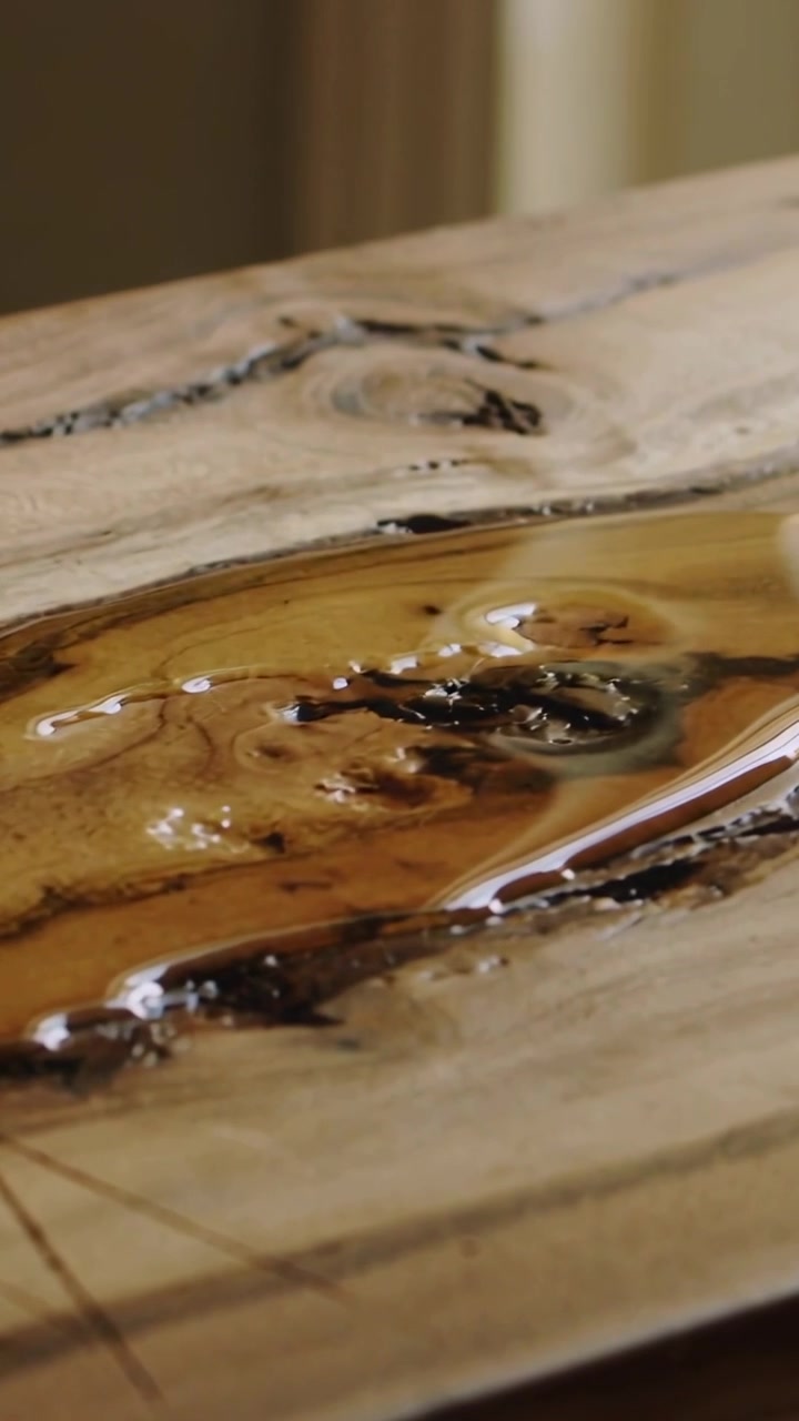 Vertical video: Panning camera revealing live-edge slab in studio, showing amber resin and grain