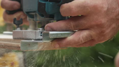 Hands-of-man-working-with-wood-outdoors-using-electrical-machine,-close-up