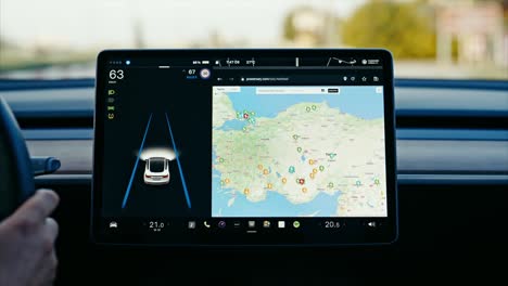 close-up of tesla car sensor touchscreen monitor with different apps, functions and capabilities, autonomous navigating system controlling road traffic, speed and battery