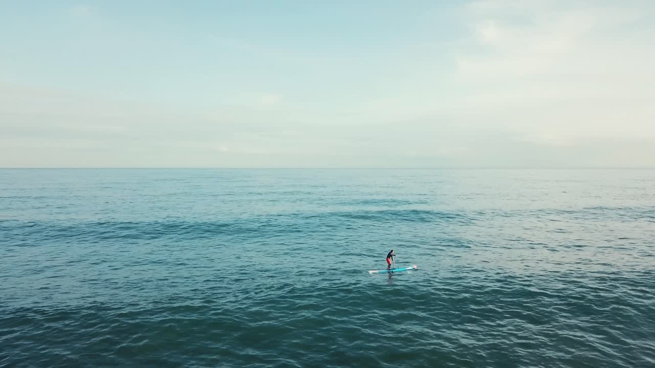 persona de pie haciendo paddleboard en el océano