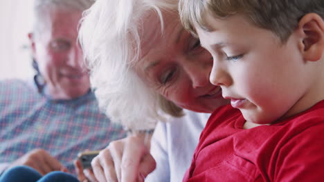 grandparents playing video games with grandchildren on mobile phones at home