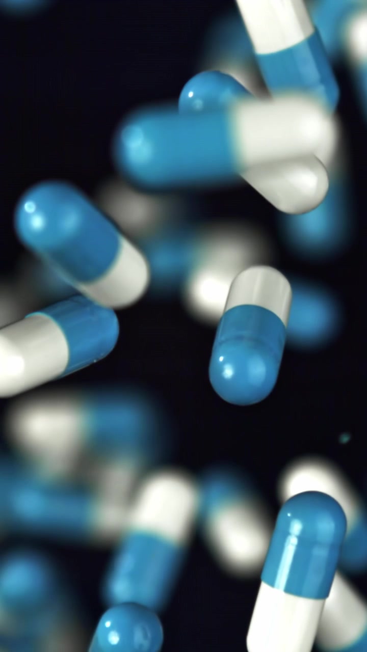 Capsule mediche blu e bianche che cadono su uno sfondo scuro