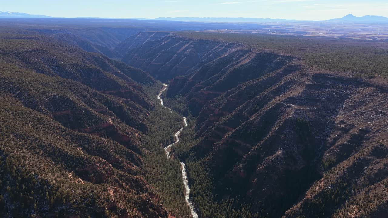 A dramatic aerial perspective reveals the massive scale of Colorado's Dolores Canyon. The 4K view highlights the rugged red rock cliffs and winding river in the remote backcountry
