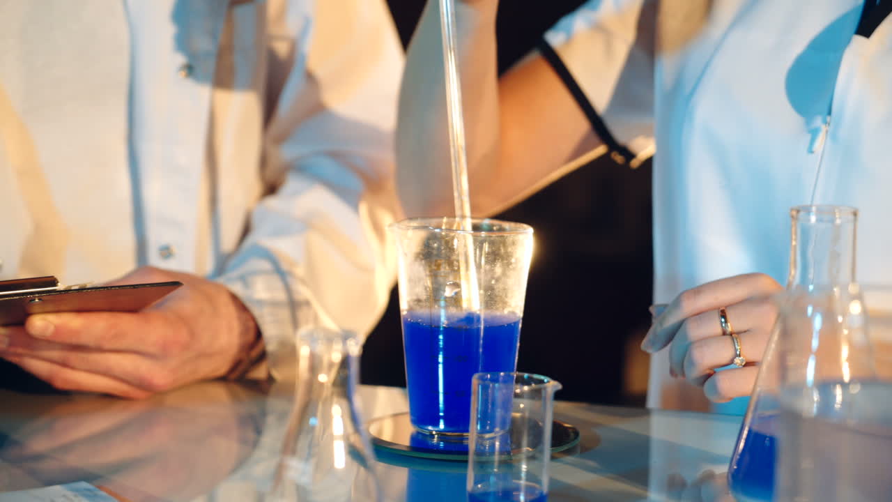Two scientists are working in laboratory. Young female and male researcher are doing investigations with test tubes.