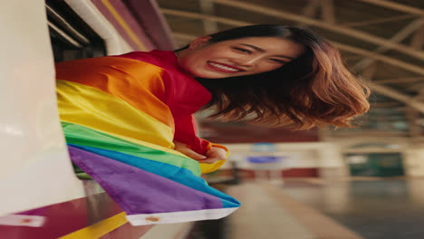 woman with pride flag at train station