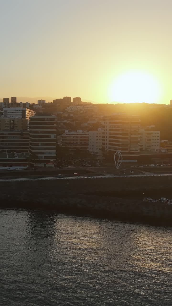 Vista aérea mostrando a vibrante paisagem urbana de Las Palmas de Gran Canaria durante um belo pôr do sol dourado, com o sol refletindo no oceano.