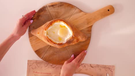 vista cercana manos de la mujer tomar khachapuri listo en la tabla marrón