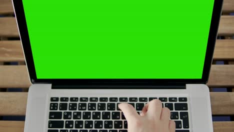 hand of man working at laptop computer typing on keyboard. green screen close up