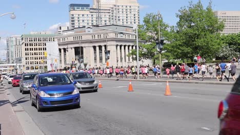 marathon runners jogging through the busy streets of ottawa, canada on a bright sunny day, wide angle.