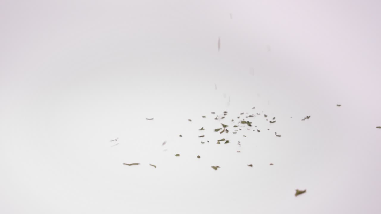 흰색 표면에 떨어지는 마른 파슬리 - 클로즈업, 느린 동작