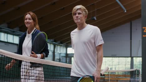 jugadores de tenis estrechando la mano en la cancha cubierta