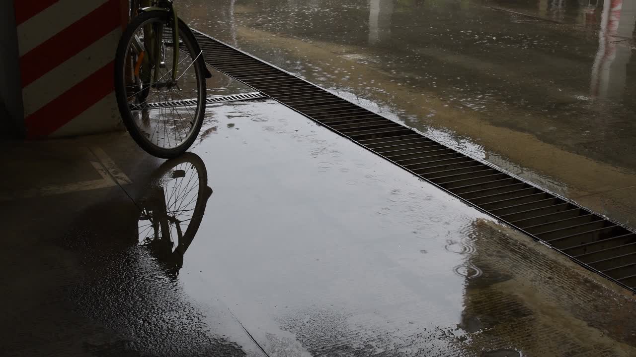 goteo de lluvia en charcos en el piso de cemento del estacionamiento urbano con bicicleta