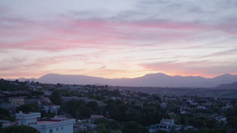 Colorful-and-pink-sunset-or-sunrise-over-a-neighborhood-with-a-landscape-of-hills