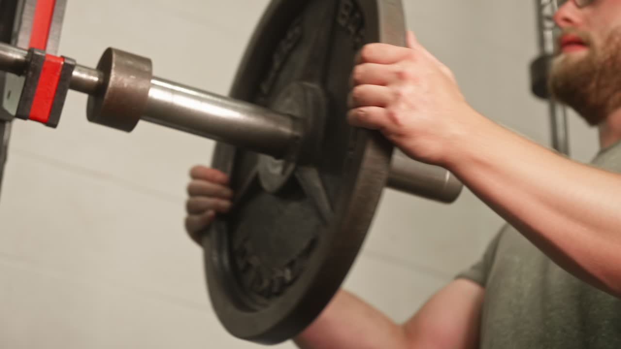 바벨에서 45파운드 웨이트 플레이트를 미끄러지는 남자의 손, 미디엄 샷, 로우 앵글, 슬로우 모션