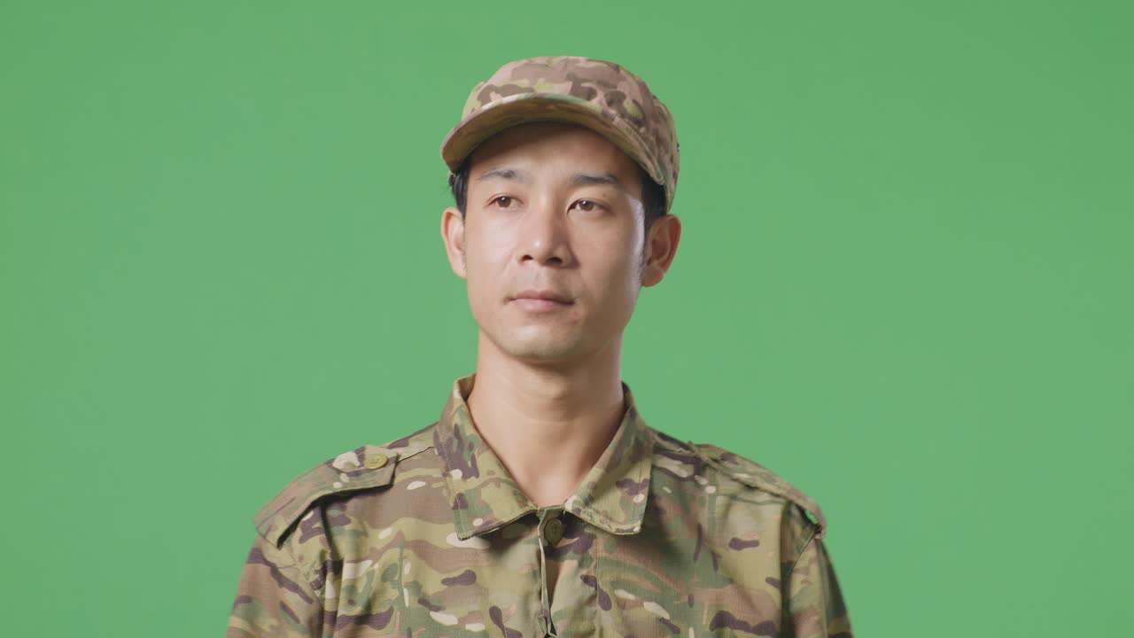 녹색 스크린 배경 스튜디오에서 걸어다니고 둘러보는 아시아 남자 군인의 클로즈업