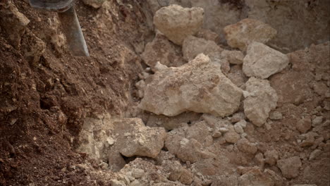 Slow-motion-close-up-of-an-hydraulic-hammer-attached-throwing-away-rocks-and-debris-at-a-construction-site