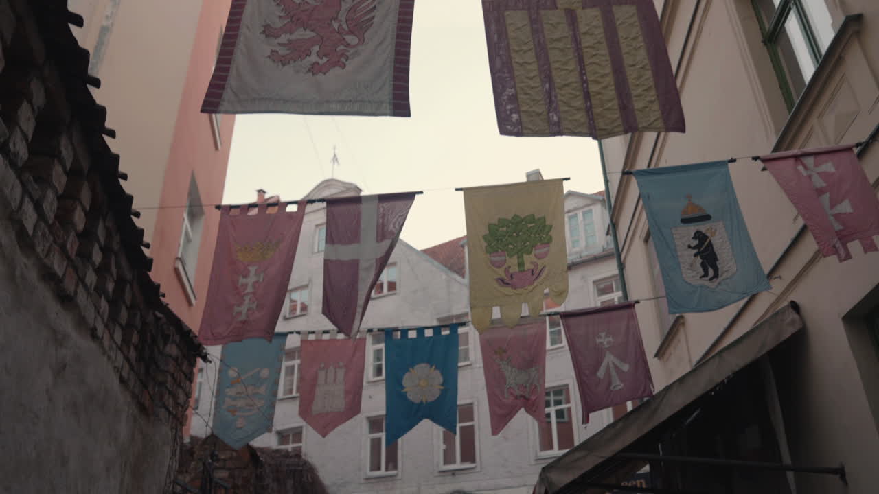 Pedestrians walking POV below flags hanging above streets in Riga, Latvia, during the winter holiday season