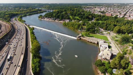 beautiful high aerial descending shot above schuylkill river, with express traffic, green park, and philadelphia residential areas during sunny summer day