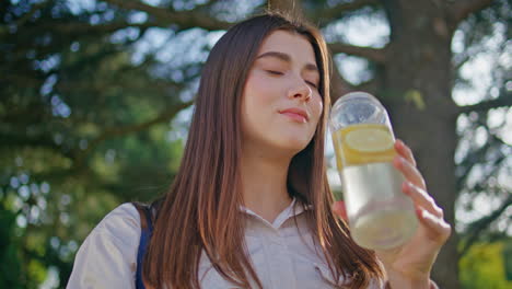 sunlight lady enjoy drink in vibrant park closeup. woman sipping lemon water