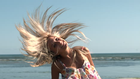 happy blonde shaking hair on the beach