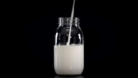 milk being poured into jars with straws